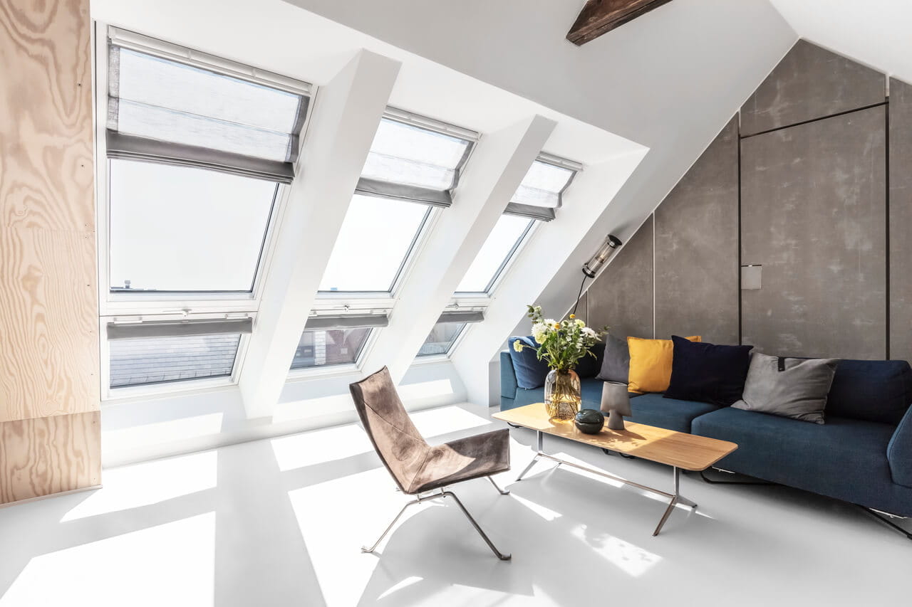 Living space with couch, table and chair in a room with three roof windows side by side