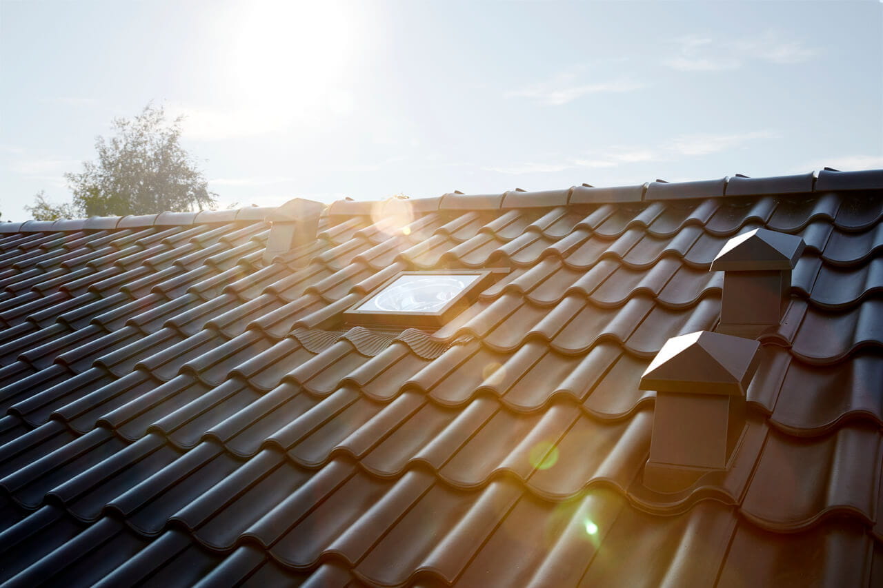 Exterior view of a VELUX sun tunnel installed in a black tiled sloped roof